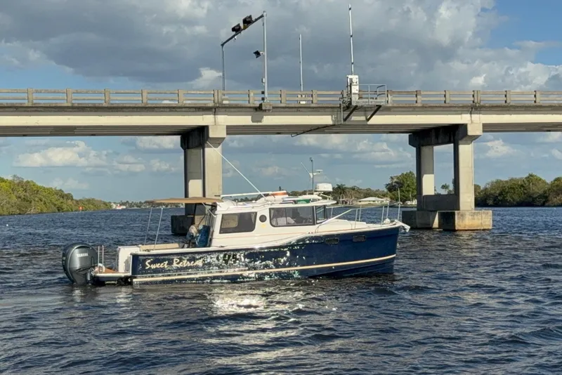 Slide: The Image of 2022 Ranger Tugs R-27 boat on water near a bridge under a cloudy sky. - 84