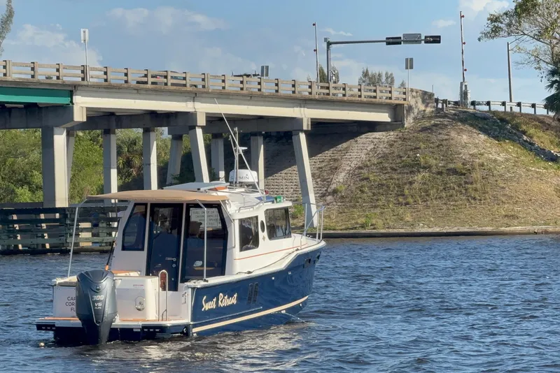 Slide: The Image of 2022 Ranger Tugs R-27 boat cruising under a bridge on a sunny day. - 86