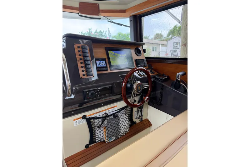 Slide: The Image of 2022 Ranger Tugs R-27 helm with navigation controls and wooden steering wheel. - 91