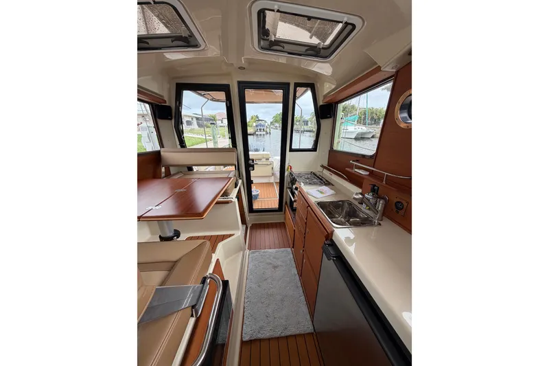 Slide: The Image of Interior of 2022 Ranger Tugs R-27 boat, featuring kitchen and dining area with scenic view. - 92