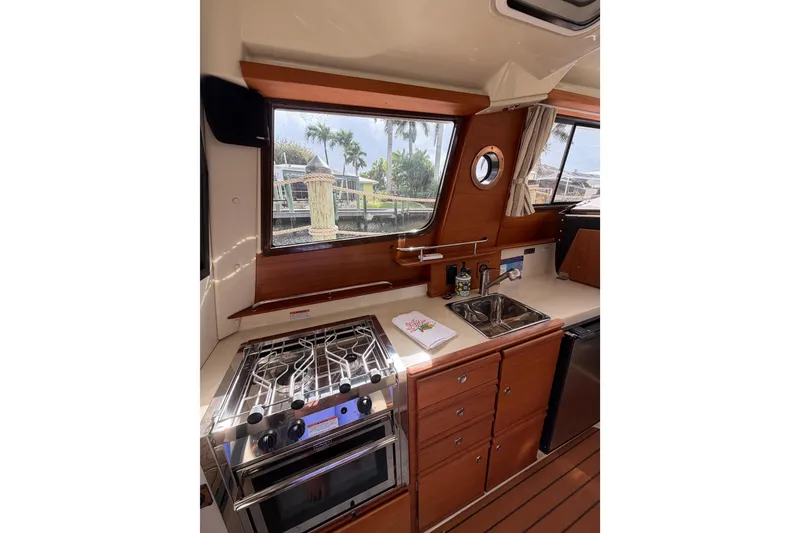Slide: The Image of 2022 Ranger Tugs R-27 interior kitchen with stove, sink, and window view. - 93