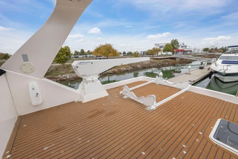 Slide: The Image of 1998 Pacific Mariner 65 yacht deck with crane, docked by a scenic waterfront. - 54
