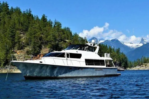 Slide: The Image of 1998 Pacific Mariner 65 yacht cruising on a scenic lake with forested mountains. - 66
