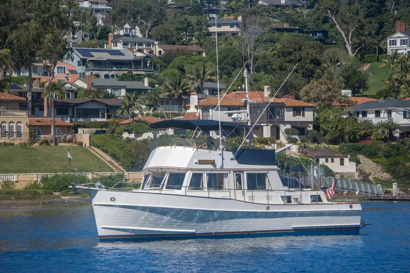 The Image of 1995 Grand Banks 42 Classic yacht cruising near coastal homes. - 0