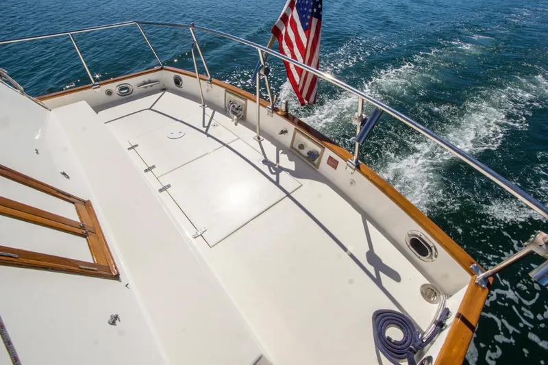 Slide: The Image of 1995 Grand Banks 42 Classic yacht deck with American flag, cruising on open water. - 10