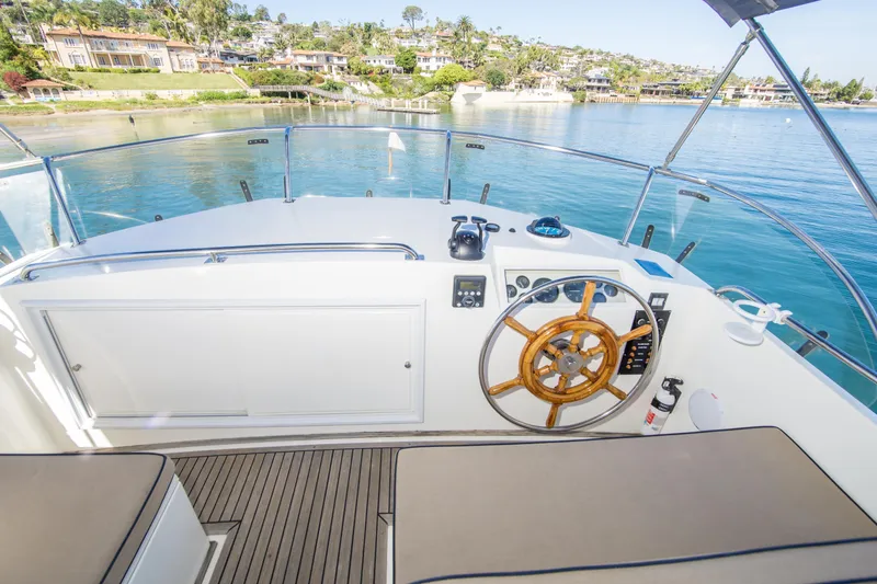 Slide: The Image of Helm of 1995 Grand Banks 42 Classic yacht with wooden steering wheel and scenic waterfront view. - 15