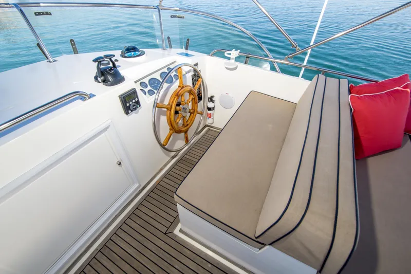 Slide: The Image of Helm of 1995 Grand Banks 42 Classic yacht with wooden wheel and cushioned seating. - 16