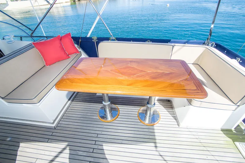 Slide: The Image of Luxury seating area on 1995 Grand Banks 42 Classic yacht with wooden table and red cushion. - 17