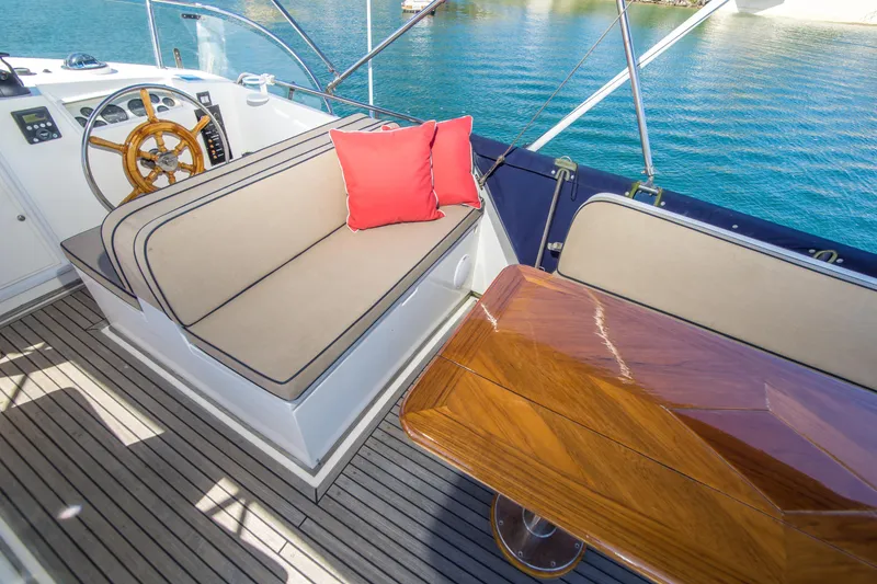 Slide: The Image of Luxury seating area on 1995 Grand Banks 42 Classic yacht with wooden table and red cushion. - 18