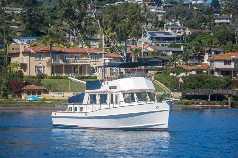 Slide: The Image of 1995 Grand Banks 42 Classic yacht cruising near luxurious waterfront homes. - 2