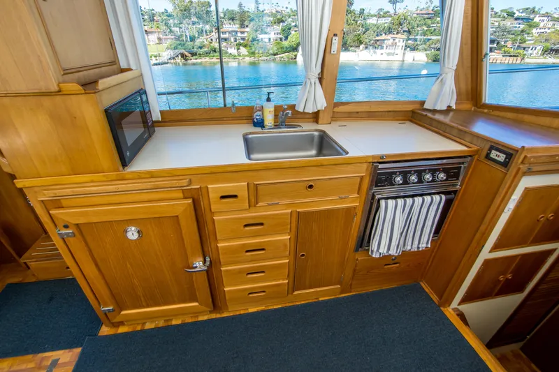 Slide: The Image of 1995 Grand Banks 42 Classic yacht kitchen with wooden cabinetry and scenic water view. - 21