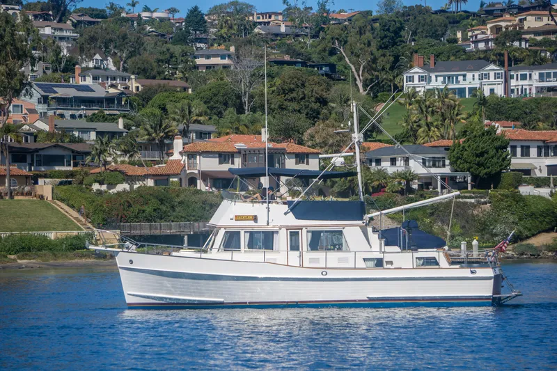 Slide: The Image of 1995 Grand Banks 42 Classic yacht cruising near scenic coastal homes. - 3