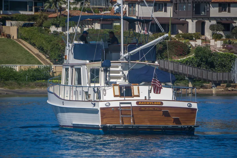 Slide: The Image of 1995 Grand Banks 42 Classic yacht on water, with American flag, near waterfront homes. - 6
