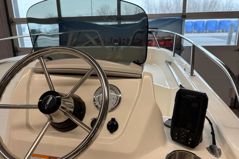 Slide: The Image of 2025 Boston Whaler 160 Super Sport boat dashboard with steering wheel and Garmin device. - 6