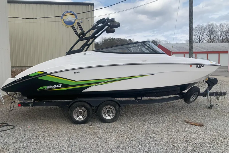 The Image of 2019 Yamaha Boats AR240 on trailer, white with green accents, parked outdoors. - 0