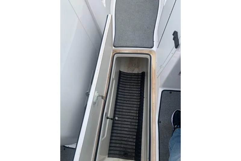 Slide: The Image of Open storage compartment on 2019 Yamaha AR240 boat, featuring a black mat inside. - 14