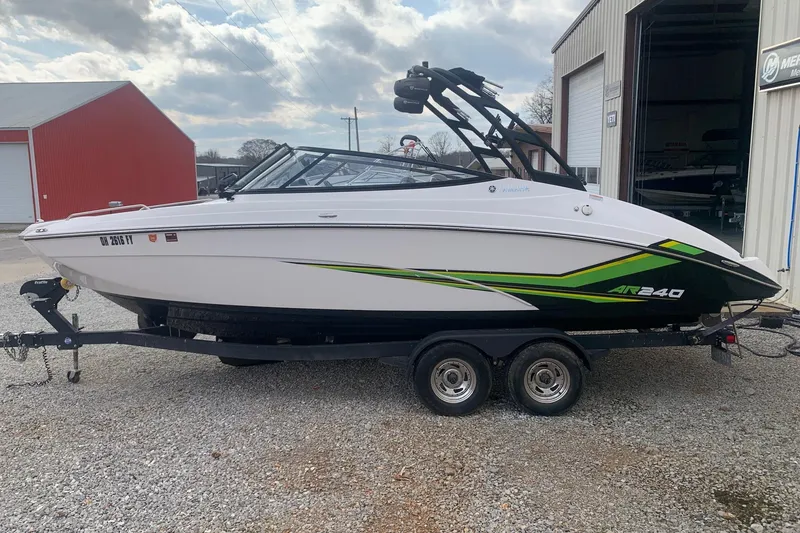 Slide: The Image of 2019 Yamaha AR240 boat on trailer, white with green accents, parked outside a building. - 4