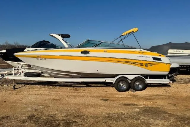 The Image of 2006 Crownline 270 BR boat with yellow accents on a trailer, parked outdoors. - 0