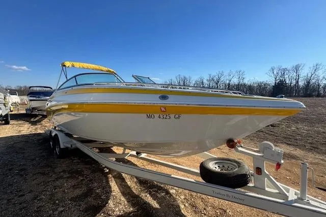 Slide: The Image of 2006 Crownline 270 BR boat on trailer, yellow accents, parked outdoors under clear blue sky. - 2