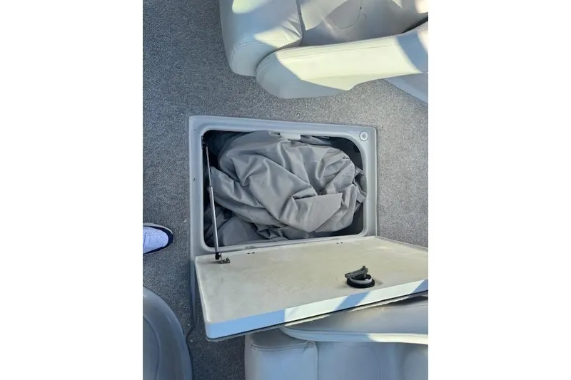 Slide: The Image of Open storage compartment on 2006 Crownline 270 BR boat with gray fabric inside. - 23