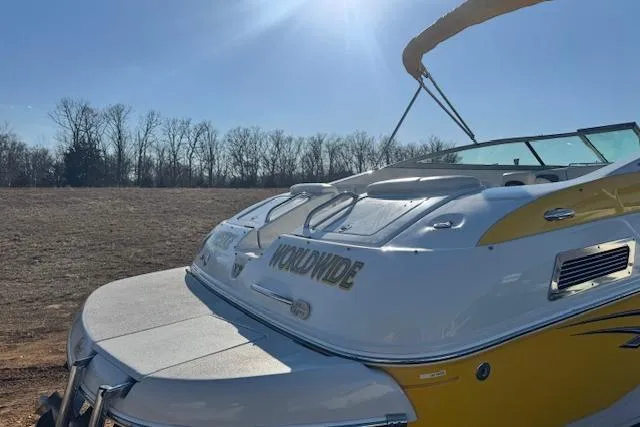 Slide: The Image of 2006 Crownline 270 BR boat with yellow accents, parked outdoors under clear blue sky. - 6