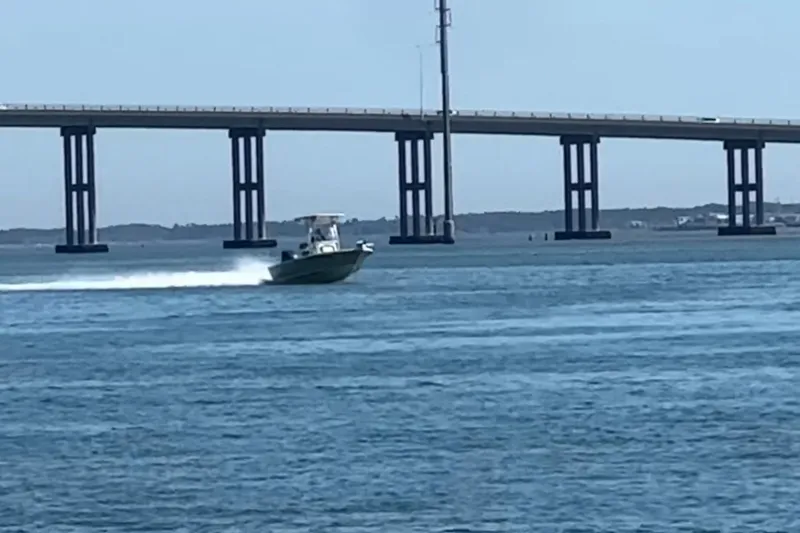Slide: The Image of 2018 Key West 230 Bay Reef boat speeding under a bridge on open water. - 13