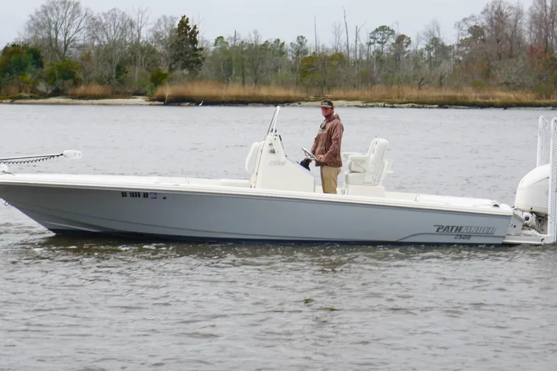 Slide: The Image of 2023 Pathfinder 2500 Hybrid boat on a calm river with a person at the helm. - 10