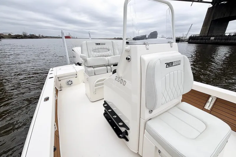 Slide: The Image of 2023 Pathfinder 2500 Hybrid boat interior with white seating, on a calm river under a bridge. - 15