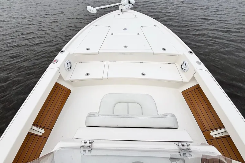 Slide: The Image of 2023 Pathfinder 2500 Hybrid boat interior with white seating and wooden accents on water. - 16