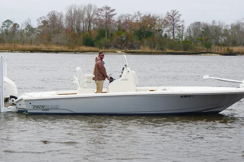 Slide: The Image of 2023 Pathfinder 2500 Hybrid boat on a calm river with trees in the background. - 4