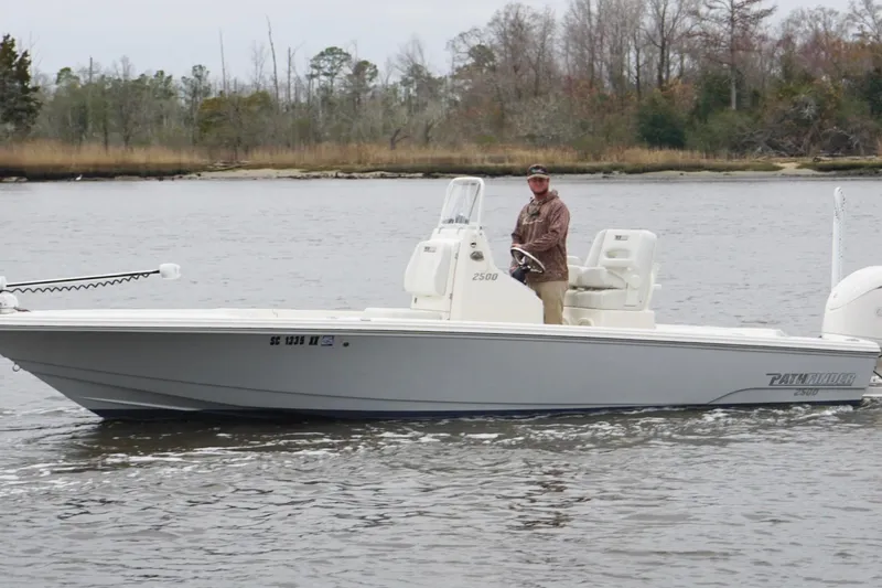 Slide: The Image of 2023 Pathfinder 2500 Hybrid boat on a calm river with a person steering. - 9