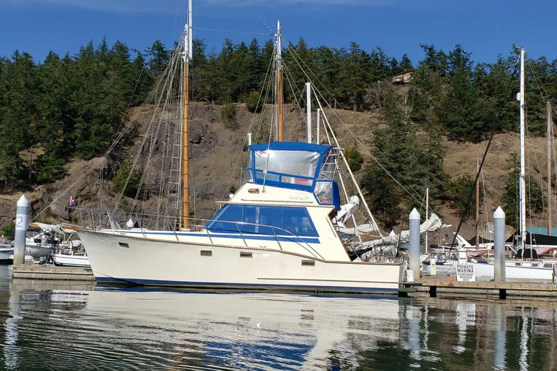 The Image of 1985 Ventura South Bay Flybridge Sedan Sport docked at a marina, surrounded by trees. - 0