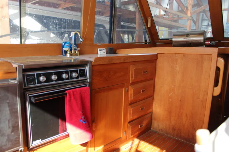 Slide: The Image of Interior of 1985 Ventura South Bay Flybridge Sedan Sport with wooden cabinetry and stove. - 11