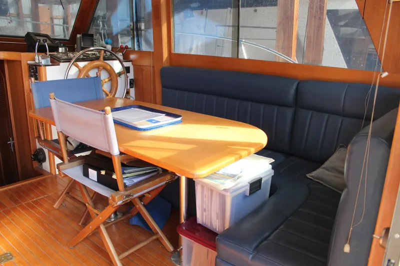 Slide: The Image of 1985 Ventura South Bay Flybridge Sedan Sport interior with wooden helm, table, and seating area. - 13