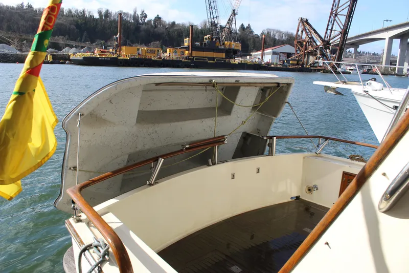 Slide: The Image of 1985 Ventura South Bay Flybridge Sedan Sport boat with open deck, docked near industrial site. - 20