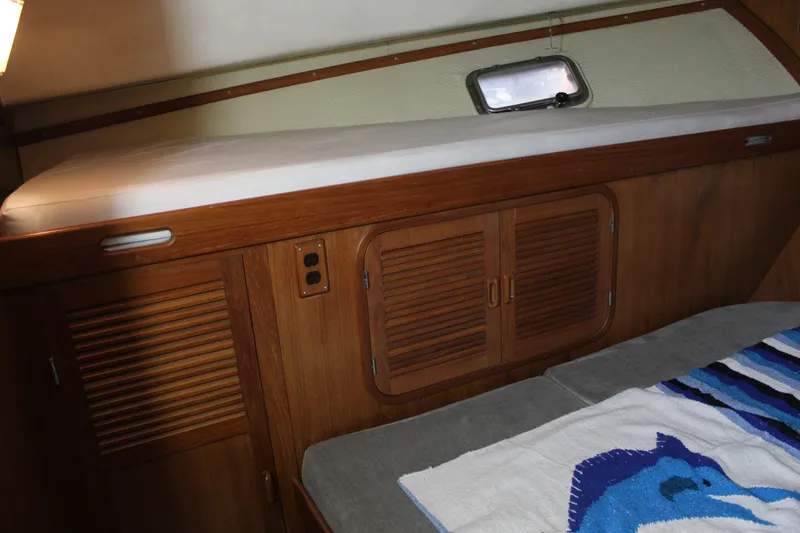Slide: The Image of 1985 Ventura South Bay Flybridge Sedan Sport cabin interior with wooden cabinetry and bedding. - 7