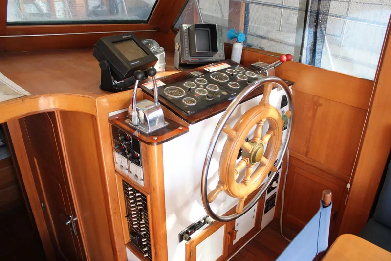 Slide: The Image of 1985 Ventura South Bay Flybridge Sedan Sport helm with wooden wheel and control panel. - 8