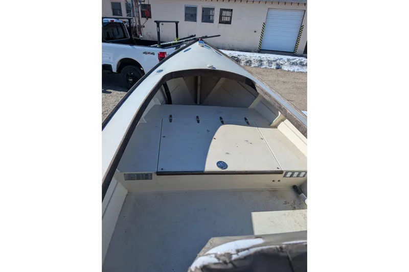 Slide: The Image of 1998 Belkov skiff boat interior with storage compartments, parked near a building. - 13