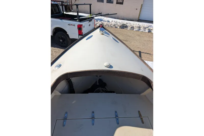 Slide: The Image of 1998 Belkov skiff boat bow view with white exterior, parked near a truck. - 20