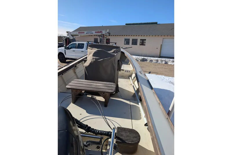 Slide: The Image of 1998 Belkov skiff boat with wooden seat, parked near a building on a sunny day. - 24