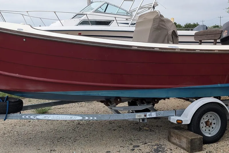 Slide: The Image of 1998 Belkov skiff on trailer, red hull, parked outdoors. - 26