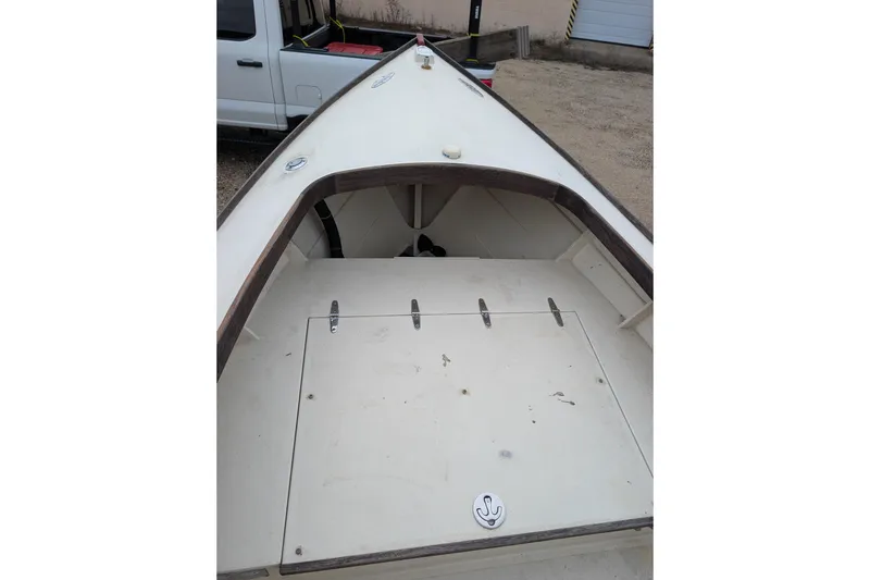 Slide: The Image of 1998 Belkov skiff boat interior with storage compartment, parked near a white vehicle. - 29