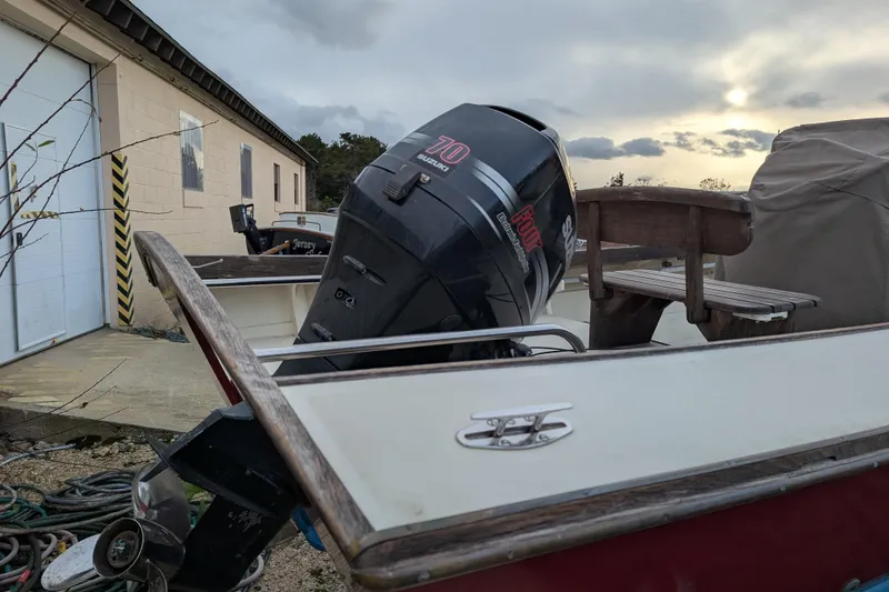 Slide: The Image of Belkov skiff boat with Suzuki outboard motor, parked near a building, cloudy sky. - 9
