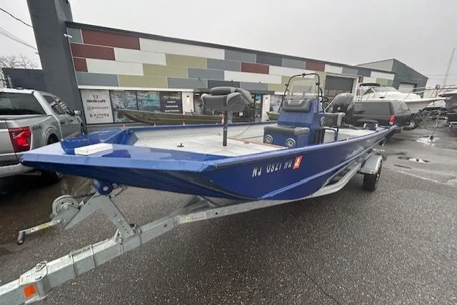 Slide: The Image of 2024 Lund 2070 Predator CC boat on trailer, parked outdoors on a rainy day. - 2