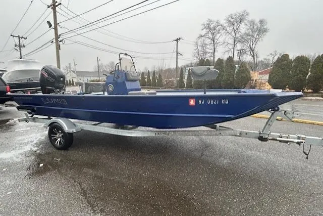 Slide: The Image of 2024 Lund 2070 Predator CC boat on trailer, parked outdoors on a cloudy day. - 5