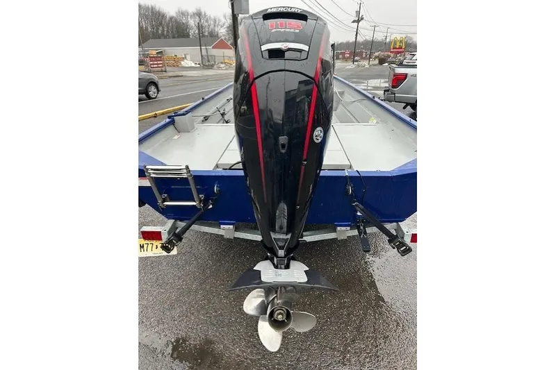 Slide: The Image of 2024 Lund 2070 Predator CC boat with Mercury 115 outboard motor, parked on a trailer. - 6