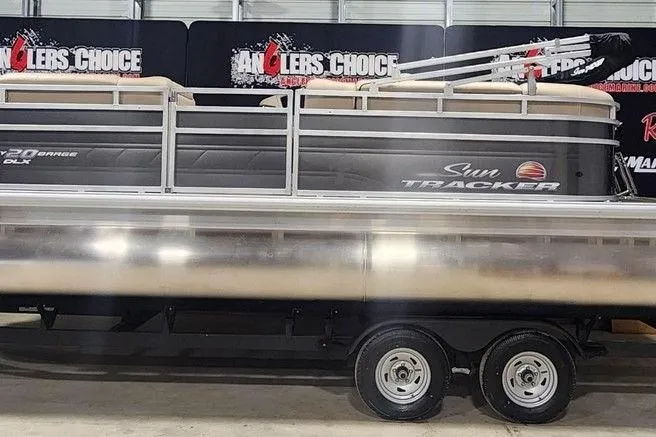 The Image of 2025 Sun Tracker Party Barge 20 DLX pontoon boat on trailer in showroom. - 1