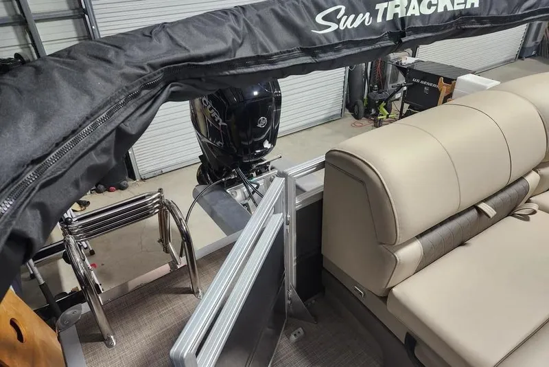 Slide: The Image of 2025 Sun Tracker Party Barge 20 DLX interior with seating and motor in a garage setting. - 12