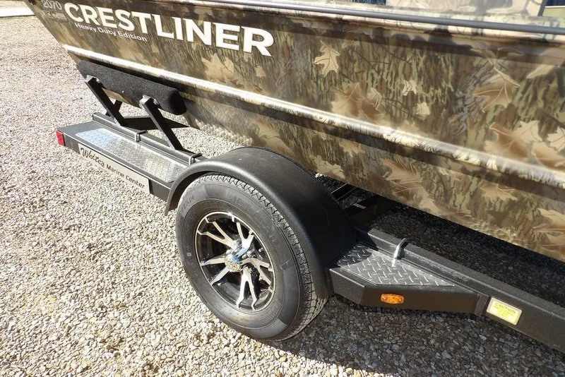 Slide: The Image of 2026 Crestliner 2070 Retriever SCHD boat on trailer, camo design, gravel background. - 41