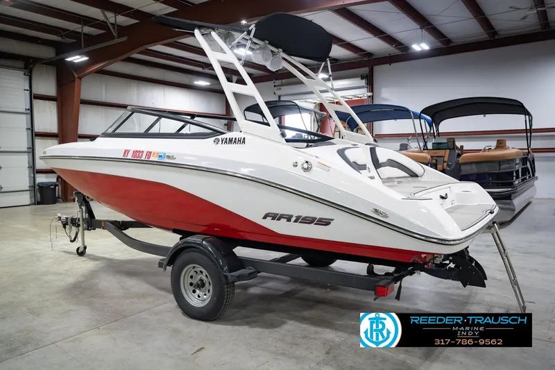 Slide: The Image of 2024 Yamaha Boats AR195 in showroom, red and white design, on trailer. - 10